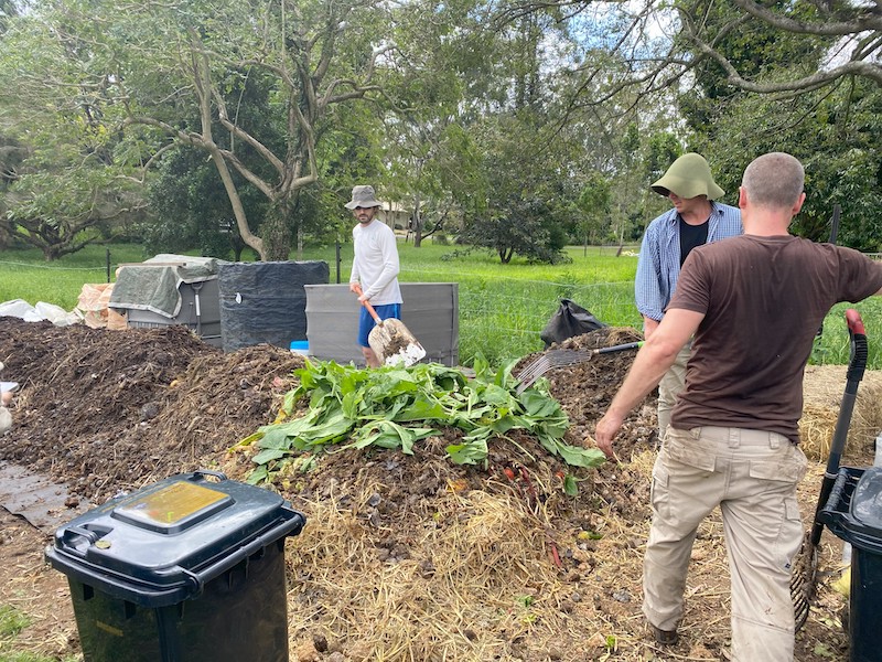 Community composter shovel fresh materials onto an open windrow