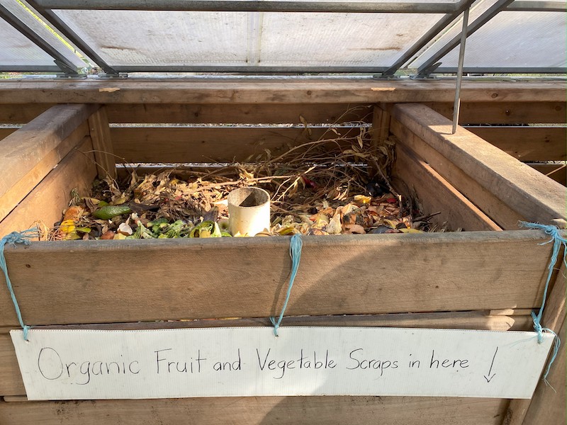 An open compost bay with a sign reading "Organic Furit and Vegetable Scraps in here"